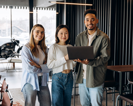 three young professionals collaborating with a laptop in a modern workspace