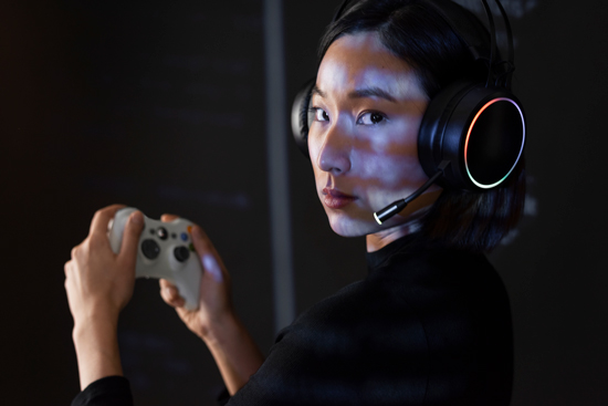 woman with gaming headset holding controller in a dark environment focused on gaming experience and technology 4 gaming accessories