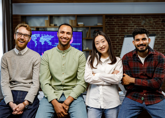 four diverse colleagues smiling together in a modern office setting with a map on the wall teamwork collaboration innovation 1
